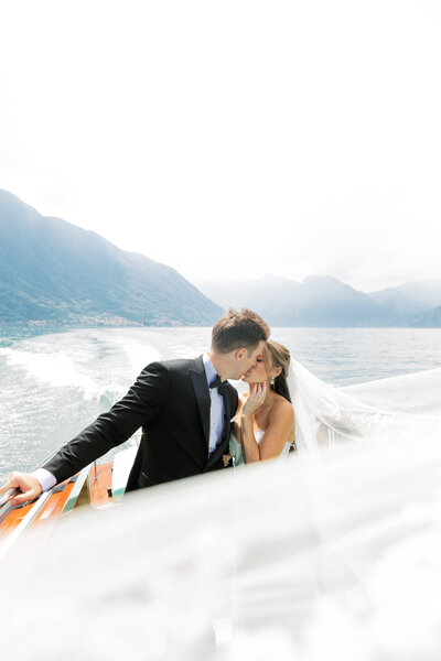 couple kissing on a boat in lake como