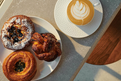 Close up photo of concrete countertop in bistro with pastries and latte