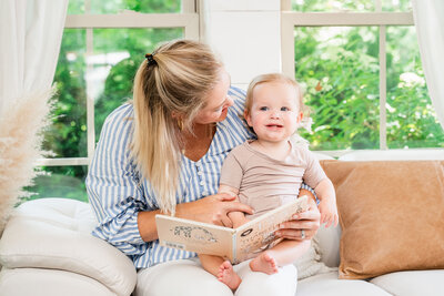 Newborn consultant reading book to infant on the couch