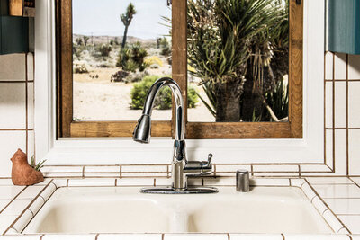 Place marketing image kitchen sink in front of window looking out to desert with cacti and Joshua Tree