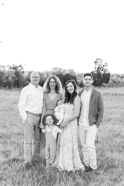 A dc maternity photography photo in black & white of an extended family looking at the camera and smiling outside in the Spring