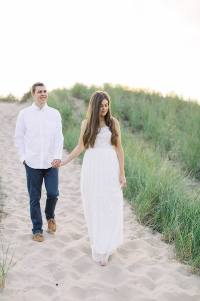 Engaged couple walking along Minnesota beach