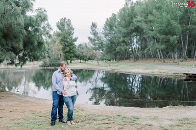 Engaged couple stand on a bridge holding hands in the Yorba Regional Park in Anaheim