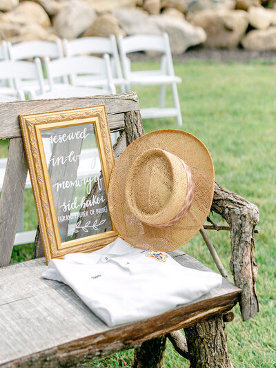 Reserved seating display at wedding ceremony with a framed sign, shirt, and hat sitting on the chair