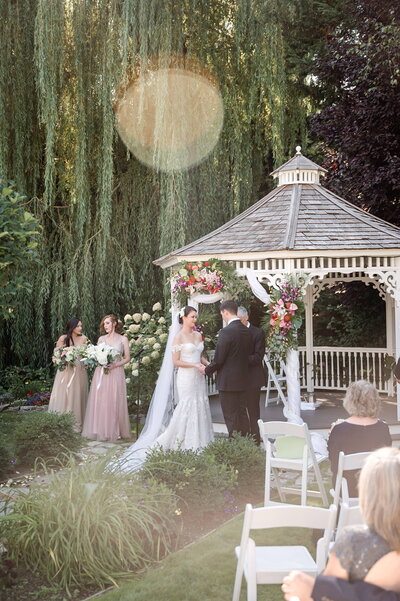 Garden wedding ceremony in front of gazebo