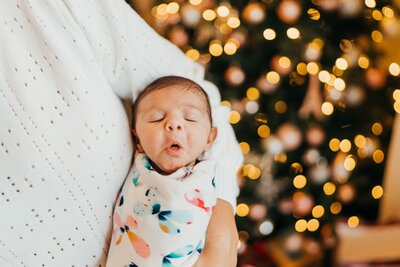 a-newborn-girl-in-mom-arm-by-Christmas-tree