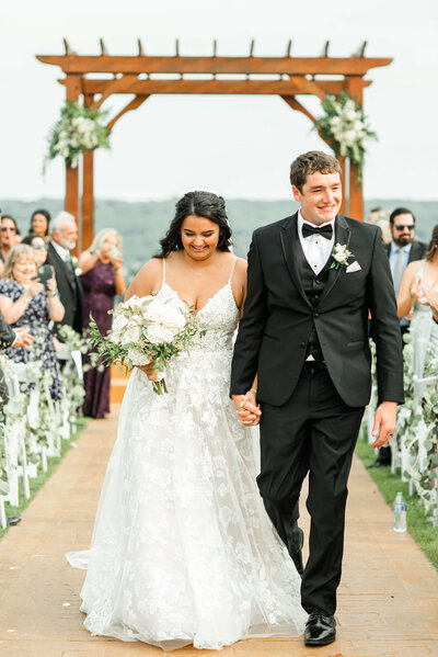 A bride and groom walking through a vineyard by Madison, WI wedding photographers Morgan Madeleine Photography