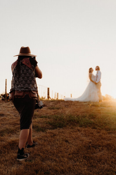 A bride and groom holding one another at sunset during a photoshoot while in the forground  Tashina Narelle, Auckland, Waikato and Tauranga Wedding Photographer takes their picture