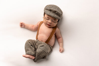 baby boy in glasses with newsboy hat by philadelphia newborn photographer