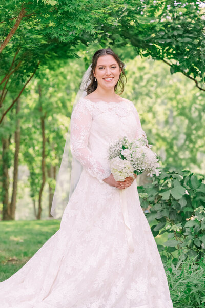 A smiling brunette bride during her bridal portraits on a wooden porch in the Blue Ridge Mountains on her wedding day by JoLynn Photography