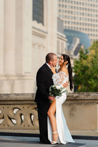 a bride and groom kiss and laugh outside the Chateau Laurier captured by Ottawa wedding photographer JEMMAN Photography