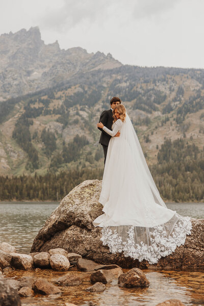 bride and groom embracing by lake