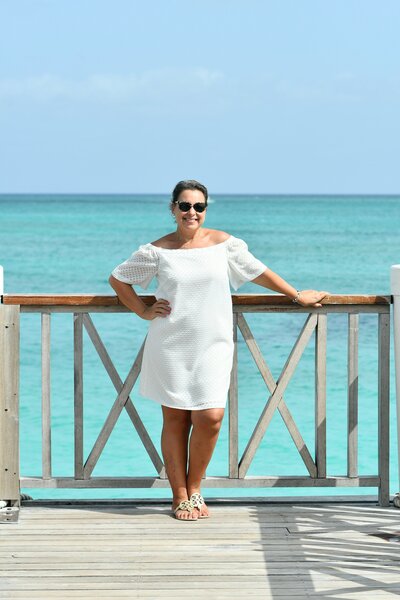 Woman in white dress standing on deck over blue water in the Turks and Caicos