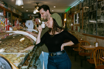 man and woman smiling while drinking espresso and looking at pastries