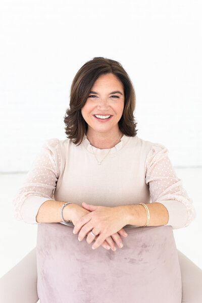 Dallas Photographer, Danielle Maggio, smiles for portait in pink sweater