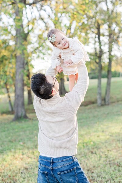 Dad tossing little girl up in the air during spring family session in Nashville