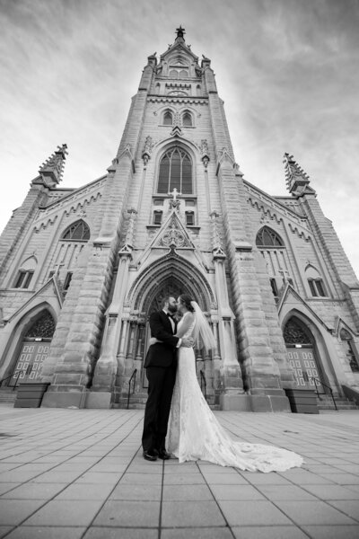 A dramatic black and white wedding photo in front of a church.