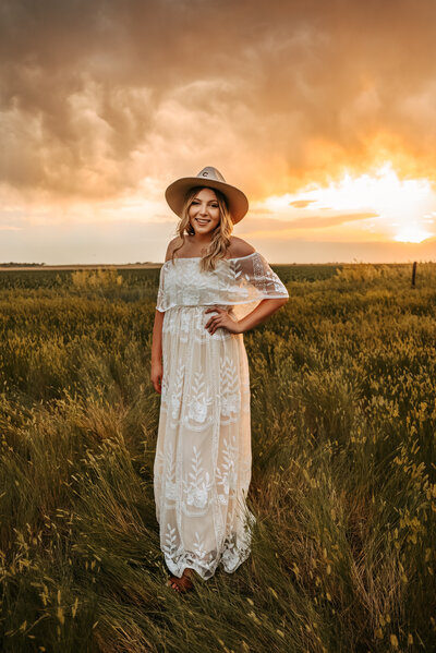 Girl in white lace dress poses in open field