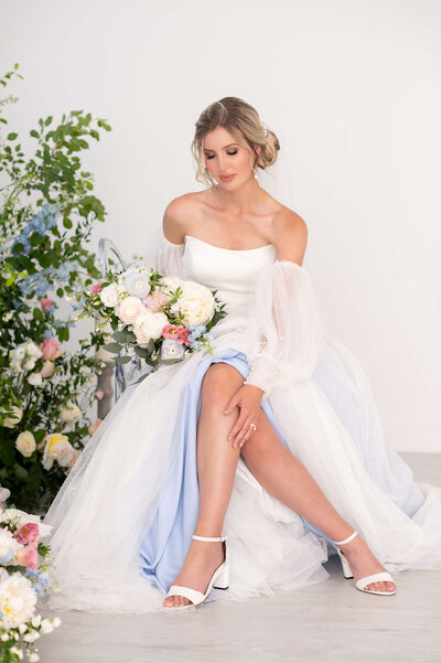 A photo of a beautiful Ottawa bride sitting down with her legs visible and crossed, holding her bouquet for her Ottawa wedding photos