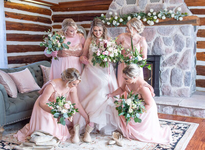 bridesmaids help a bride put her shoes on as she gets ready for First Looks for her Ottawa wedding photos at Stonefields Estate venue