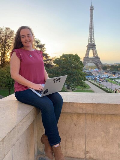 Abigail holding a computer with the Eiffel Tower in the background