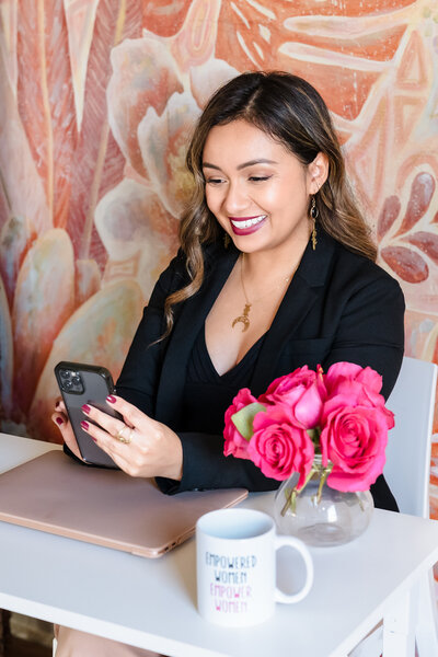 Life Coach checks her phone seated in her desk