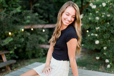 A high school senior girl sitting on a picnic table during a senior photo session.