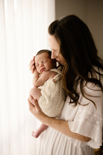 Kiri holding her newborn baby during her newborn photoshoot with new plymouth photographer aimee kelly photography