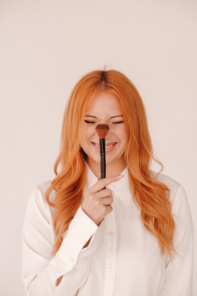 Portrait of aMakeup artist holding a make up brush up to her nose