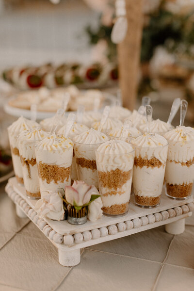 cheesecake cups with silver sprinkles on a white wooden platter
