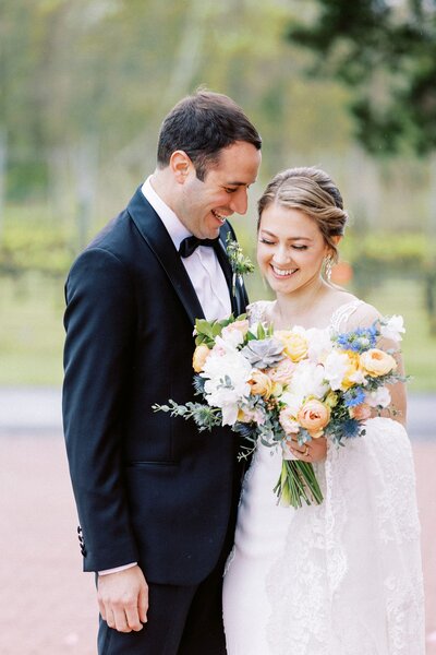 Bride and groom laughing together holding colorful bouquet at their Philadelphia wedding