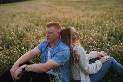 Married man and woman back to back sitting in an open field
