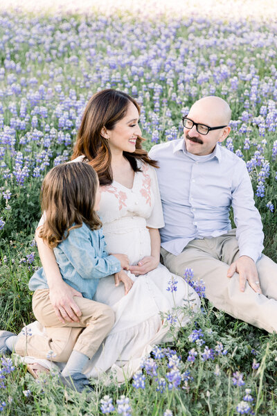 family sitting in wildflowers together looking at each other taken by maternity photographer sacramento Kelsey Krall