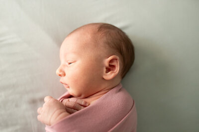newborn sleeping soundly in pink colored onesie