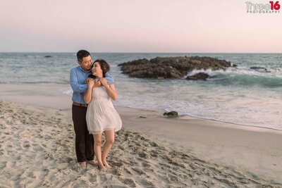Groom to be lifts his fiance in his arms as they kiss on Table Rock Beach