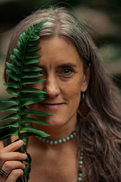 woman holding a fern leaf