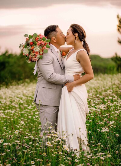Bride and groom kissing in wildflower field