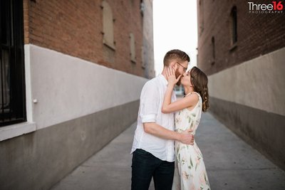 Engaged couple engage in a romantic kiss during engagement session in an alleyway in Old Towne Orange