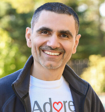Outdoor headshot of a Toronto-based kitchen reno company employee, wearing a company branded t-shirt, with a natural park setting in the background