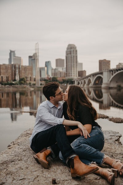 couple going in for a kiss with the minneapolis skyline behind them