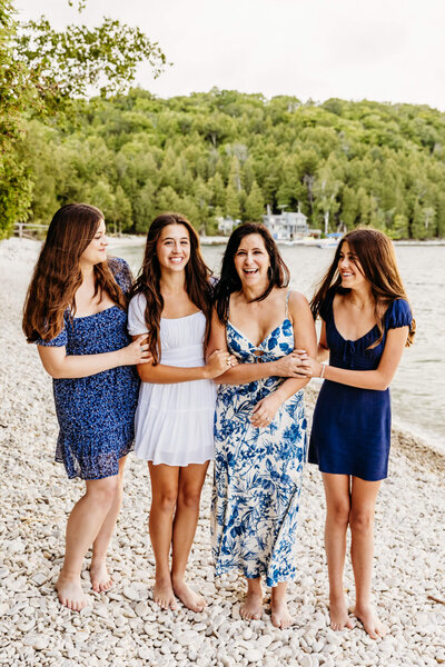 beautiful mama surrounded by her 3 daughters as they laugh while standing on a beach in  Door County