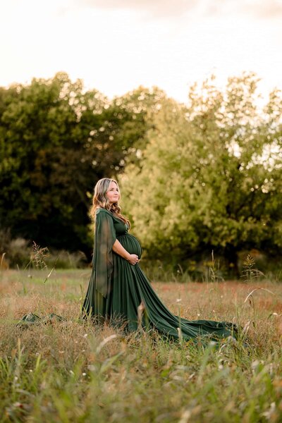 expectant mother in green maternity dress standing in a charlotte area field