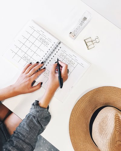 Writing in planner with straw hat