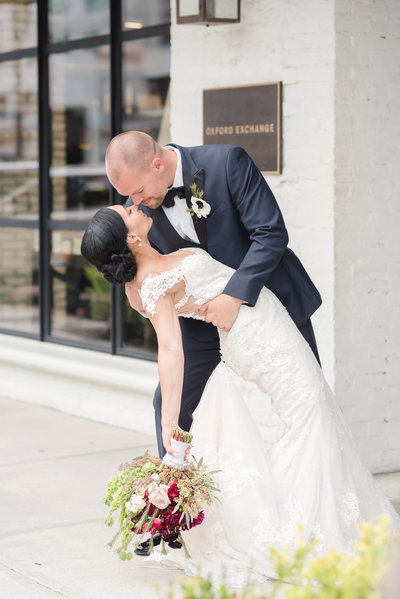 Groom dips his bride romantically on their wedding day outside the Oxford Exchange