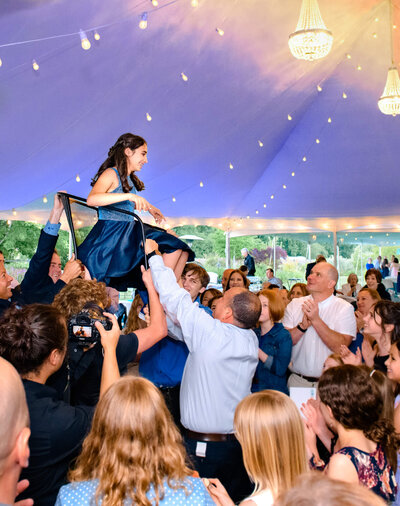 A teen girl in a blue dress sitting in a chair lifted above the dance floor