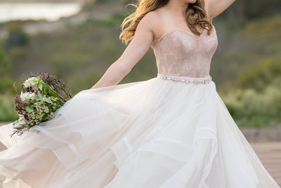 Beautiful bride in white and rose wedding dress on the beach in Santa Barbara, California