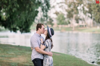 Engaged couple embrace and look into each other's eyes as they pose for photos next to the lake at Tri City Park in Placentia