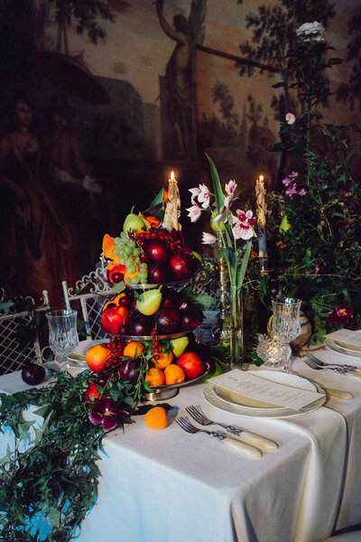 Elegant wedding tablescape with candlelight, lush fruit arrangements, and romantic florals, captured in a cinematic style by a luxury documentary wedding photographer UK.