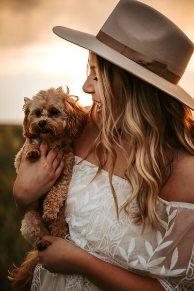 Girl looks at her small dog she is holding and smiles at it