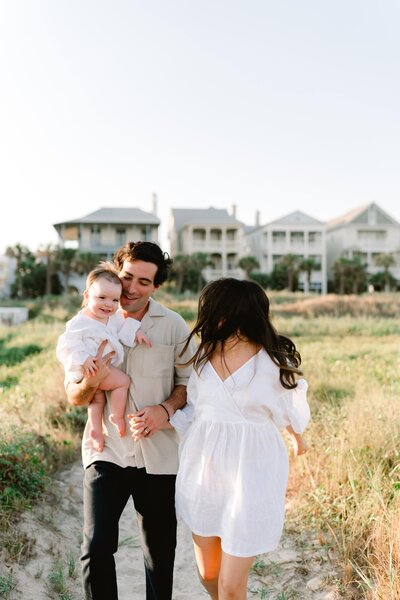 Mother and father walking to beach holding baby